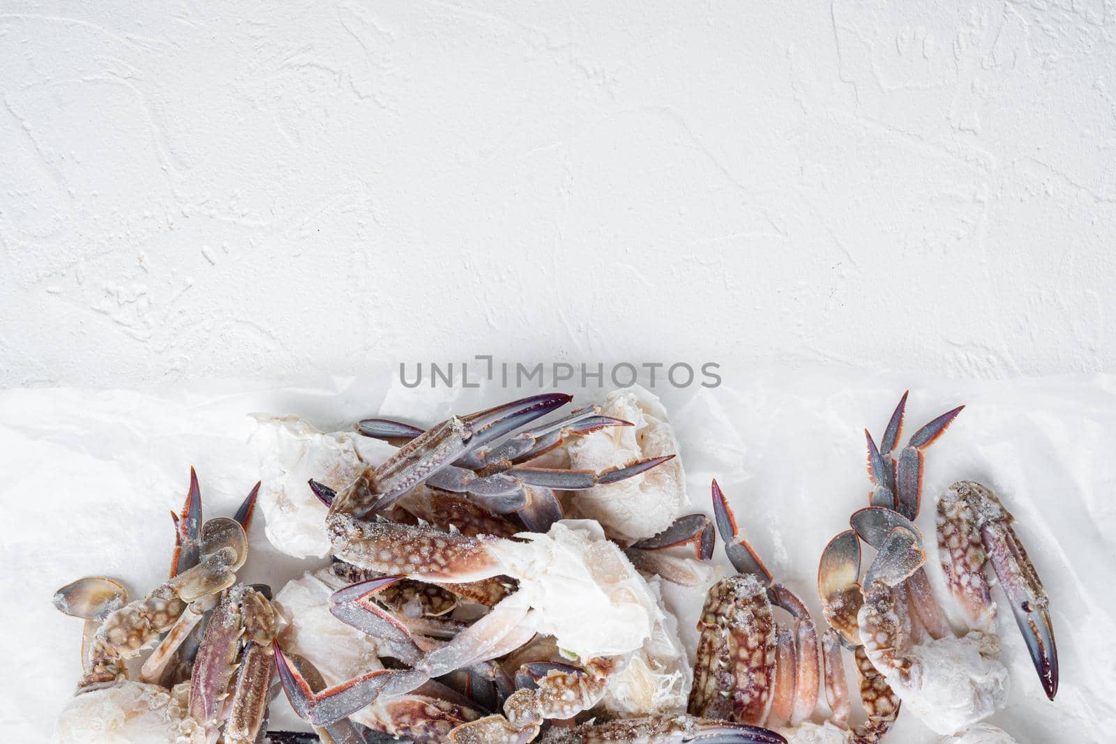 Fresh raw flower crab or blue crab frozen parts set, on white background, top view flat lay , with copyspace and space for text