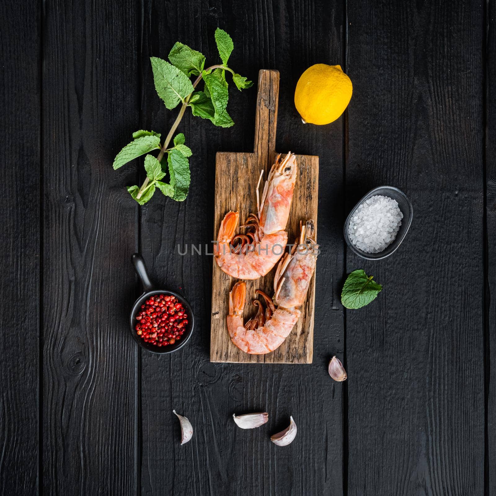 Seafood scampi on wooden board over black wood table, flat lay, food photo.