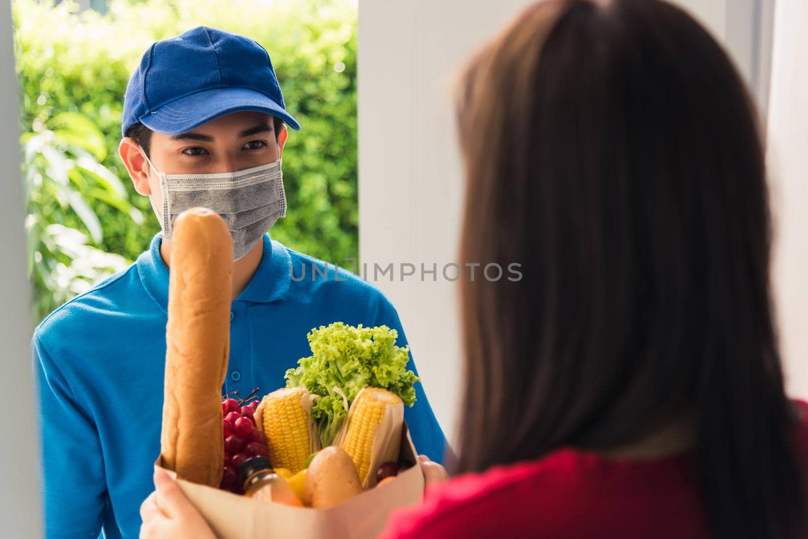 Delivery man wear protective face mask making grocery giving fresh food to woman customer by Sorapop