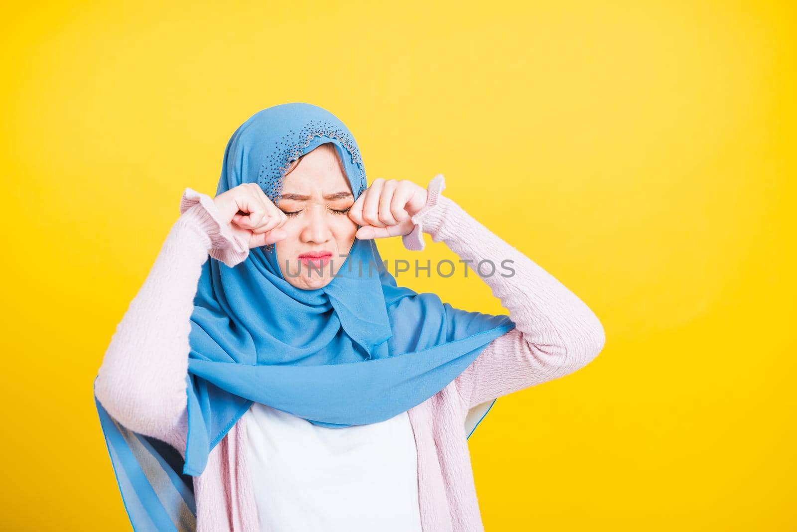 Woman wear veil hijab she sad crying using hand wiping tears in her eyes by Sorapop