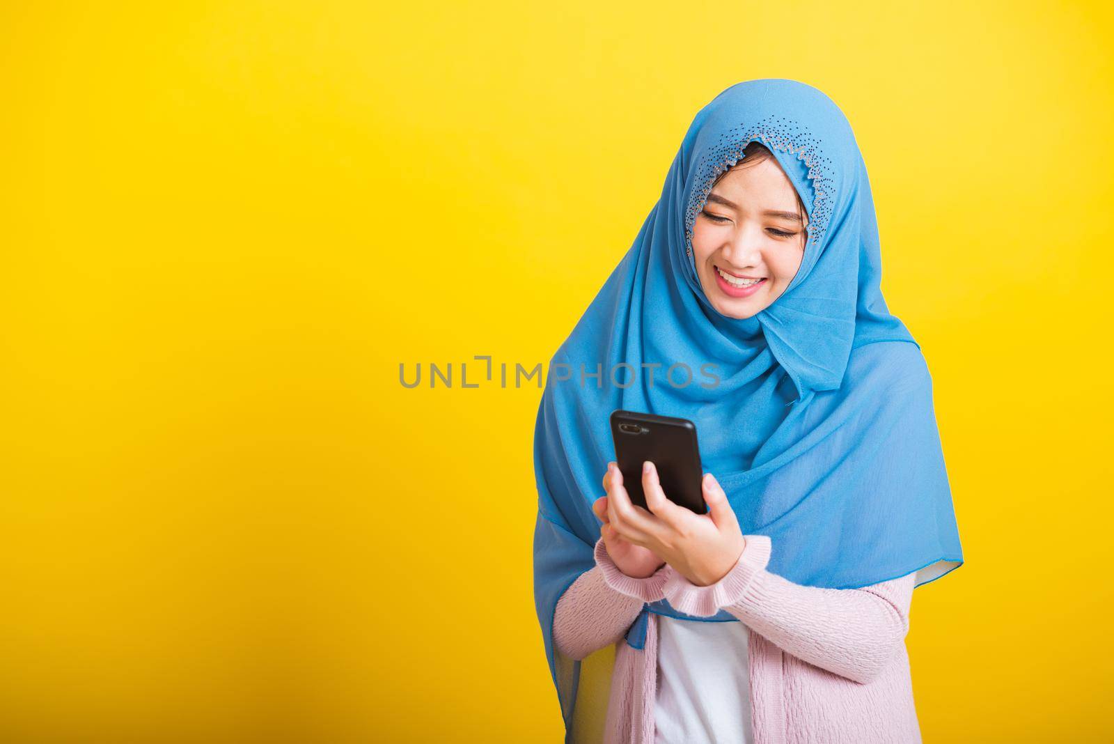 Asian Muslim Arab woman Islam wear hijab smile she using hold mobile smart phone by Sorapop