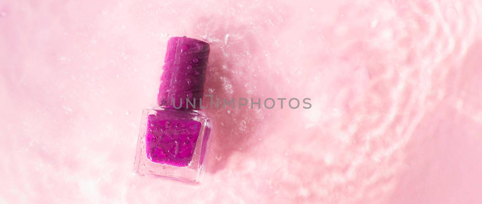 Lilac nail polish on a background with water drops . The concept of a bottle with a varnish without an inscription. Water drops. Pink background. Article about the choice of nail polish. Water-based varnish. Copy space