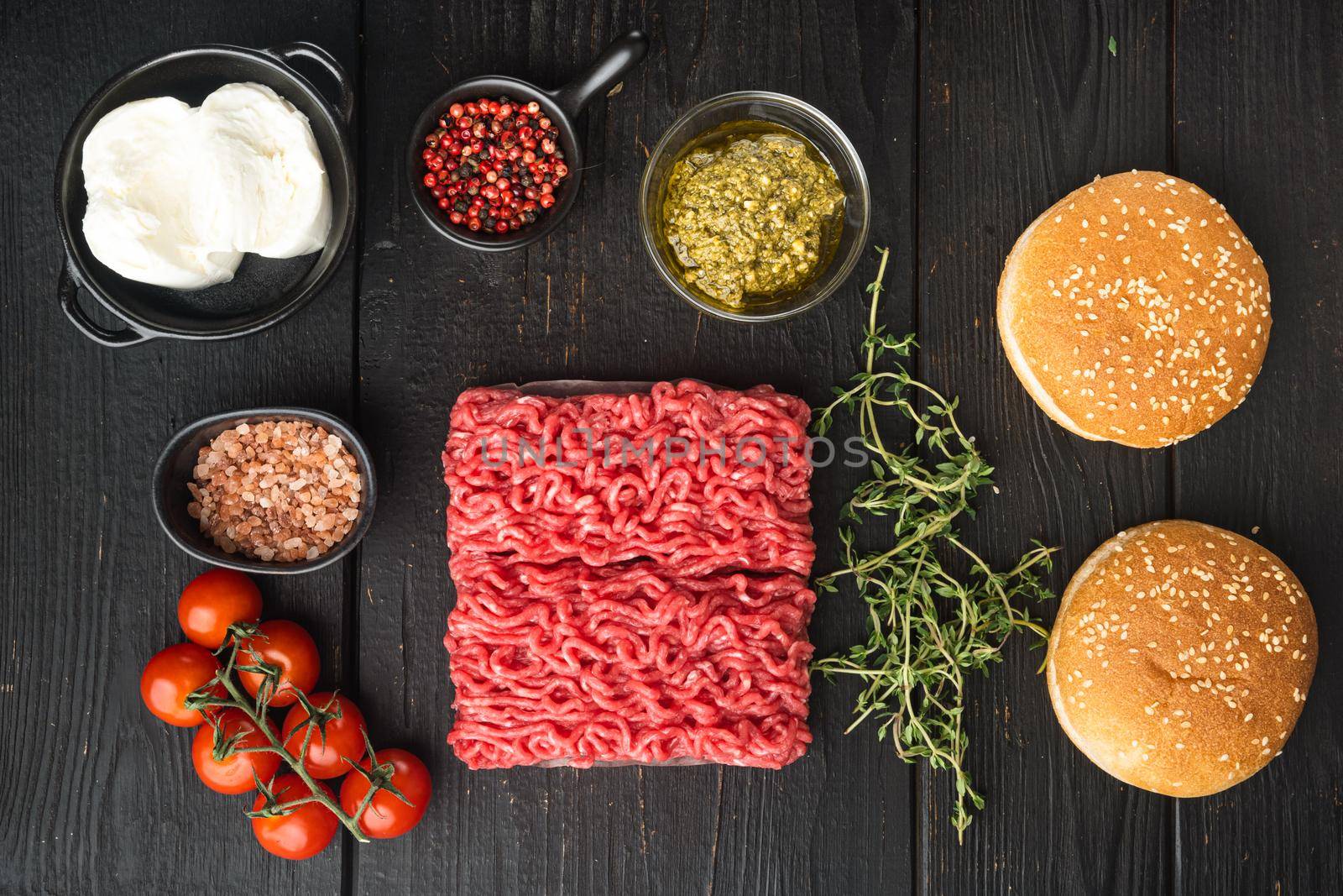 Fresh raw minced beef meat for meatball burgers with sesame buns set, on black wooden table background, top view flat lay