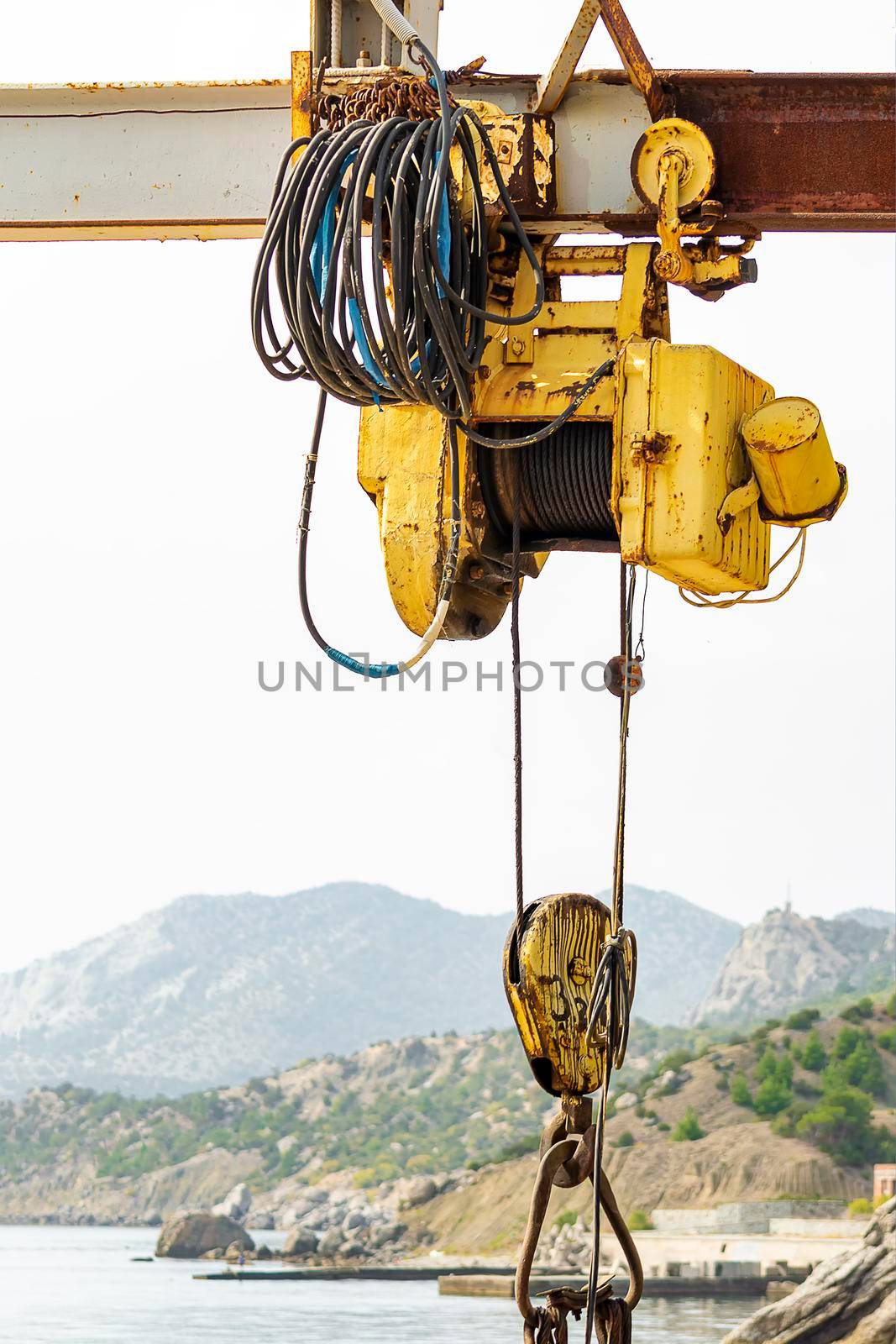 Electric hoist on beam with hook. Sunny autumn day. Side view. by Essffes