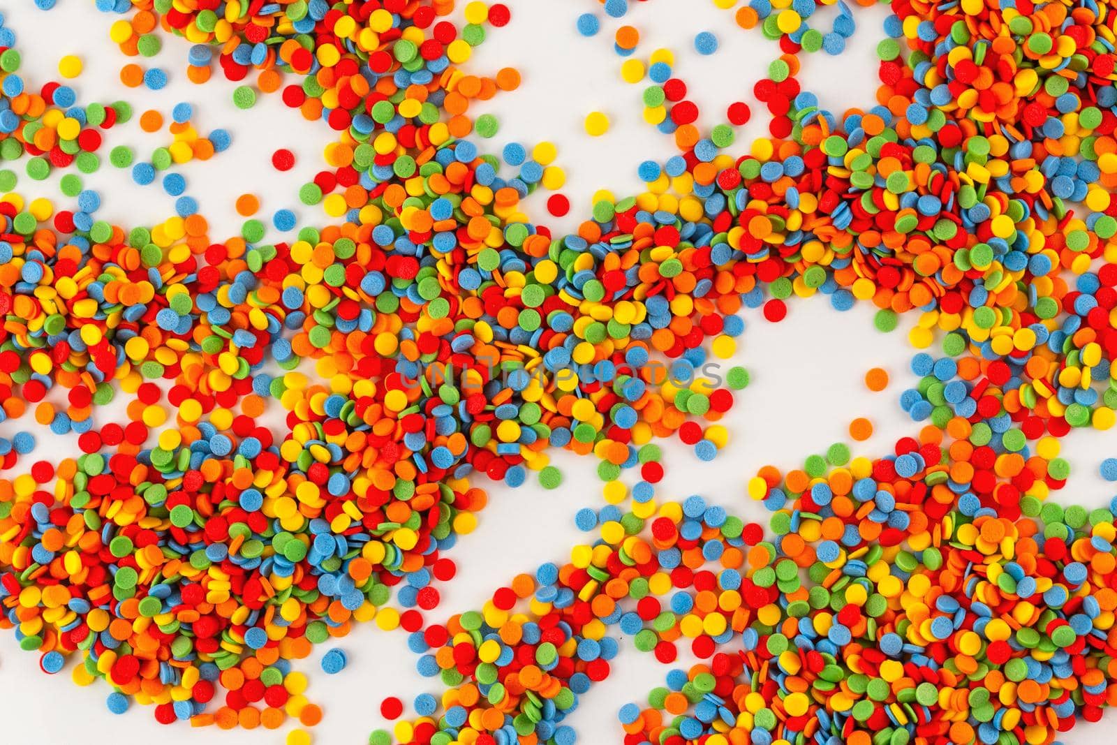 Vivid sugar sprinkle dots, decoration for cake on white background. Confectionery multicolored decorative topping.