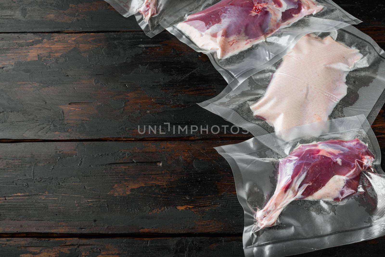 Vacuum sealed meat ready for sous vide cooking. Duck breast, legs, raw meat set, on old dark wooden table background, with copyspace and space for text