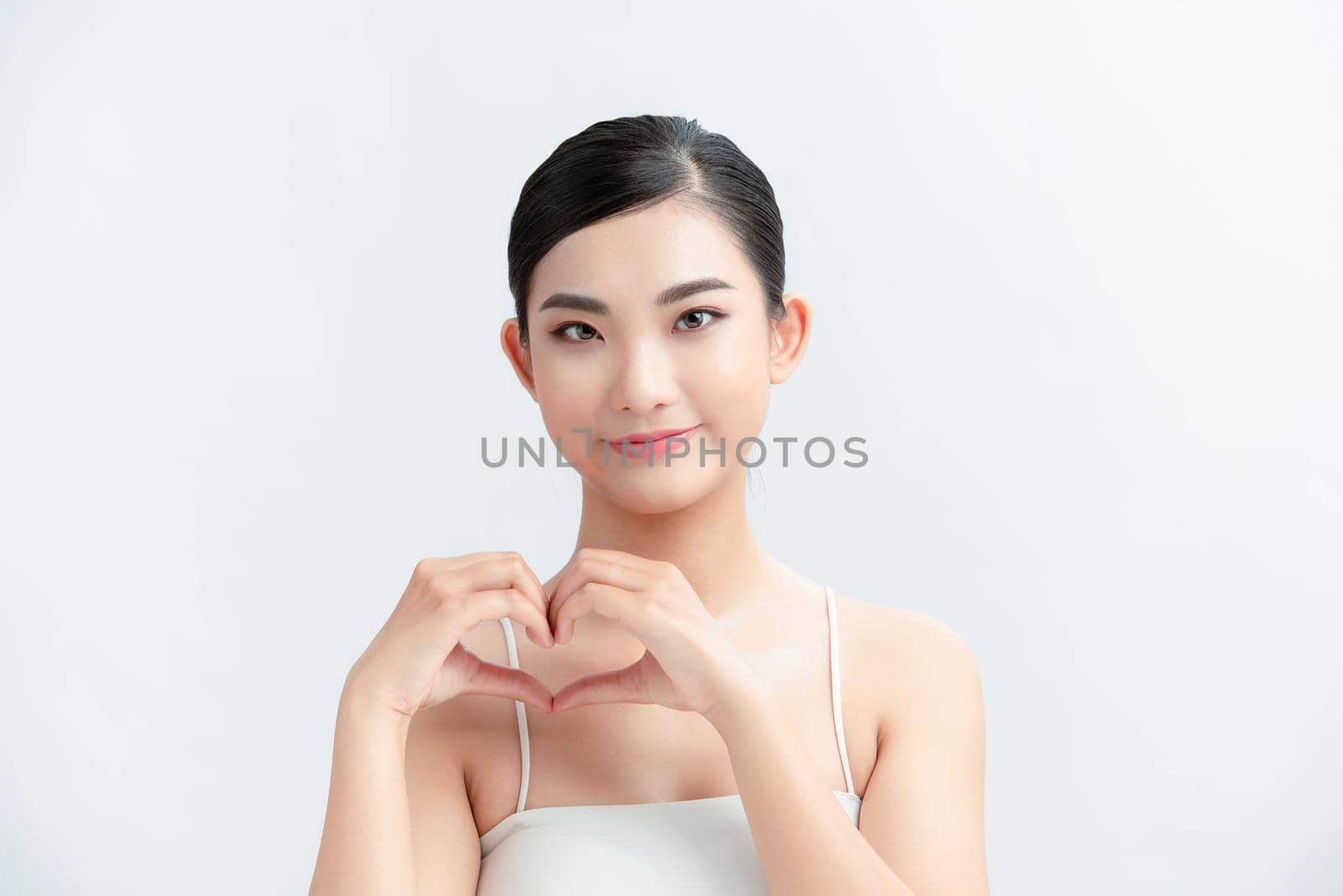 Portrait of woman showing heart figure sign with hands near chest isolated