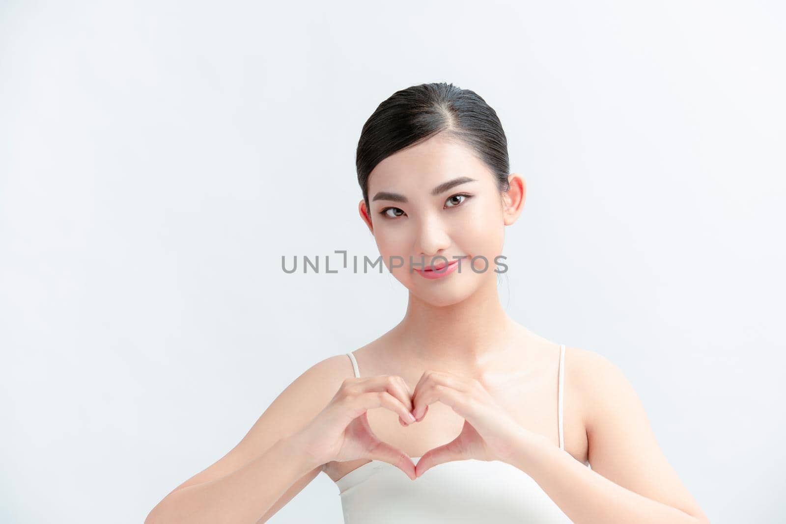 Portrait of woman showing heart figure sign with hands near chest isolated