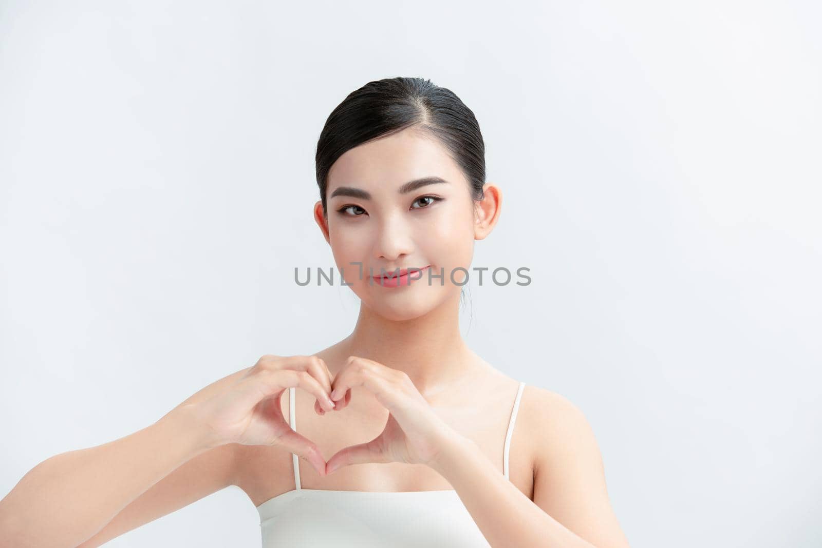 Cute Girl on a white background made a heart out of her hands near her chest
