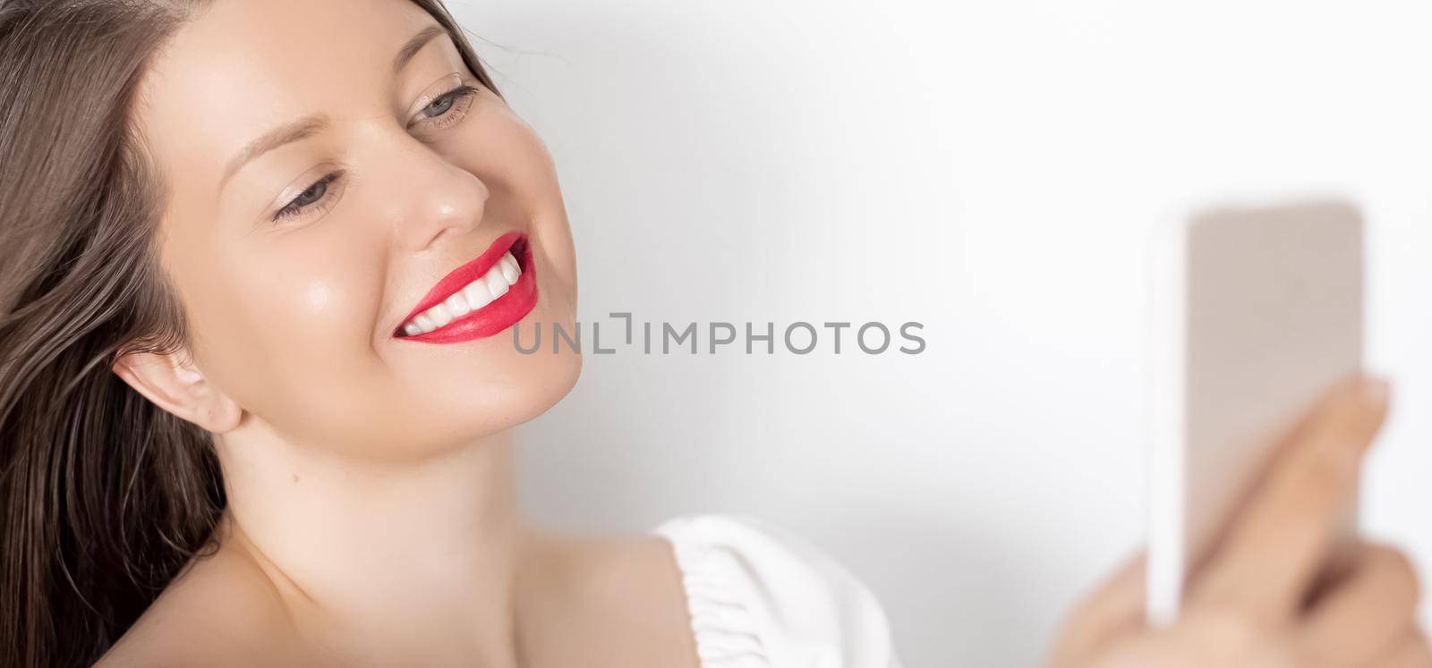 Happy smiling woman with smartphone having video call or taking selfie, portrait on white background. People, technology and communication concept.