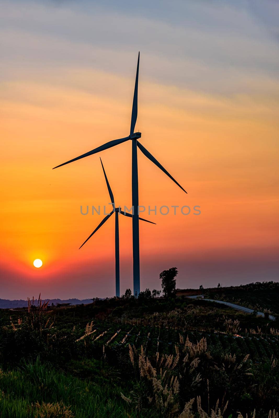 Wind turbine farm over sunset sky Generating Electricity. Renewable Power Supply