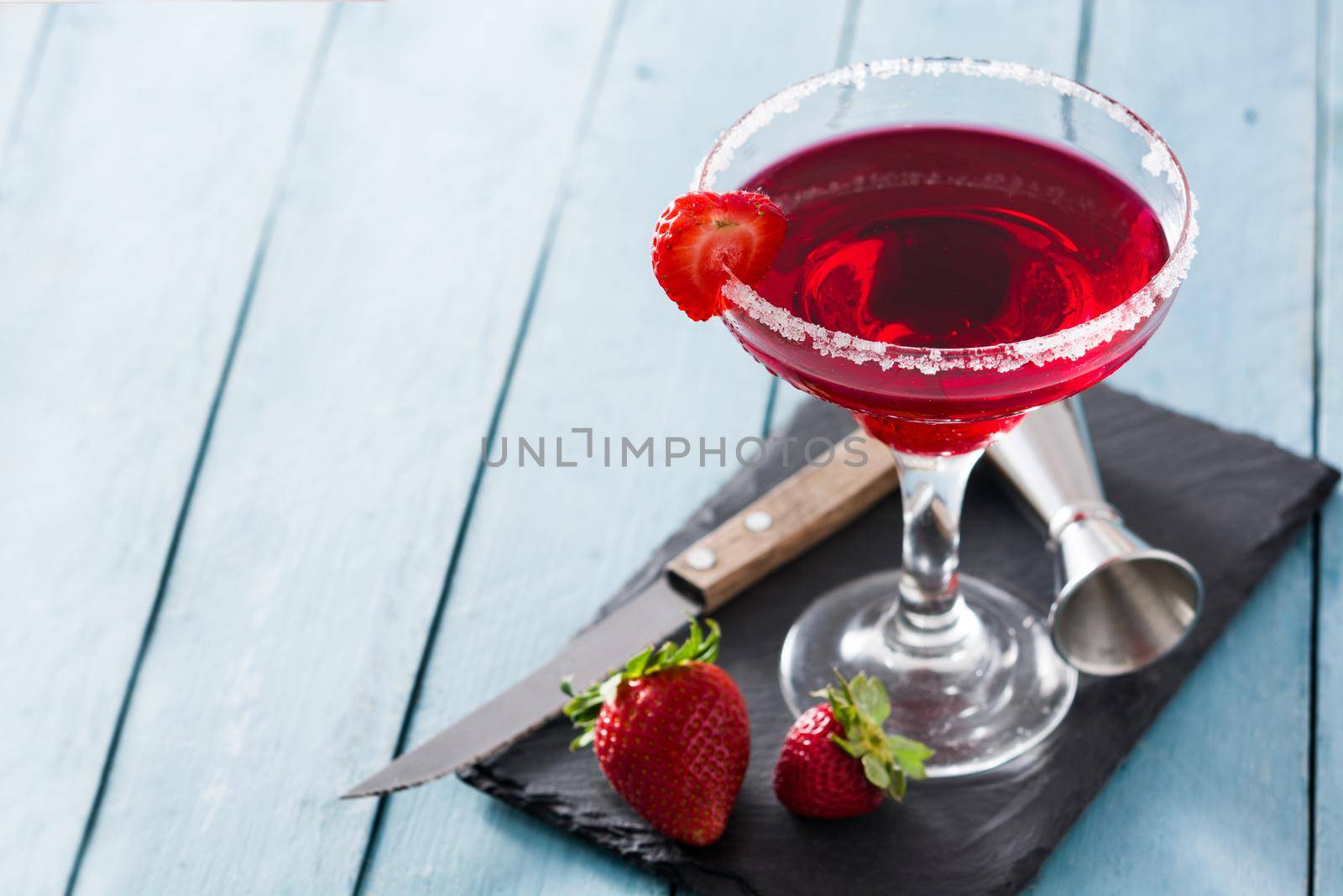 Strawberry cocktail drink in glass on blue wooden table