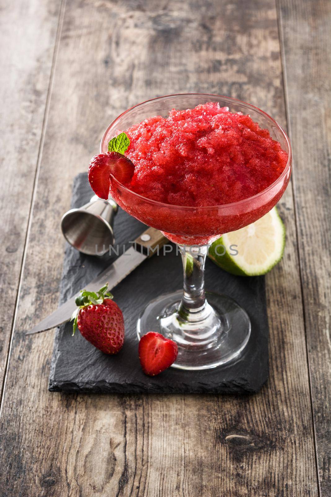 Strawberry margarita cocktail in glass on wooden table.