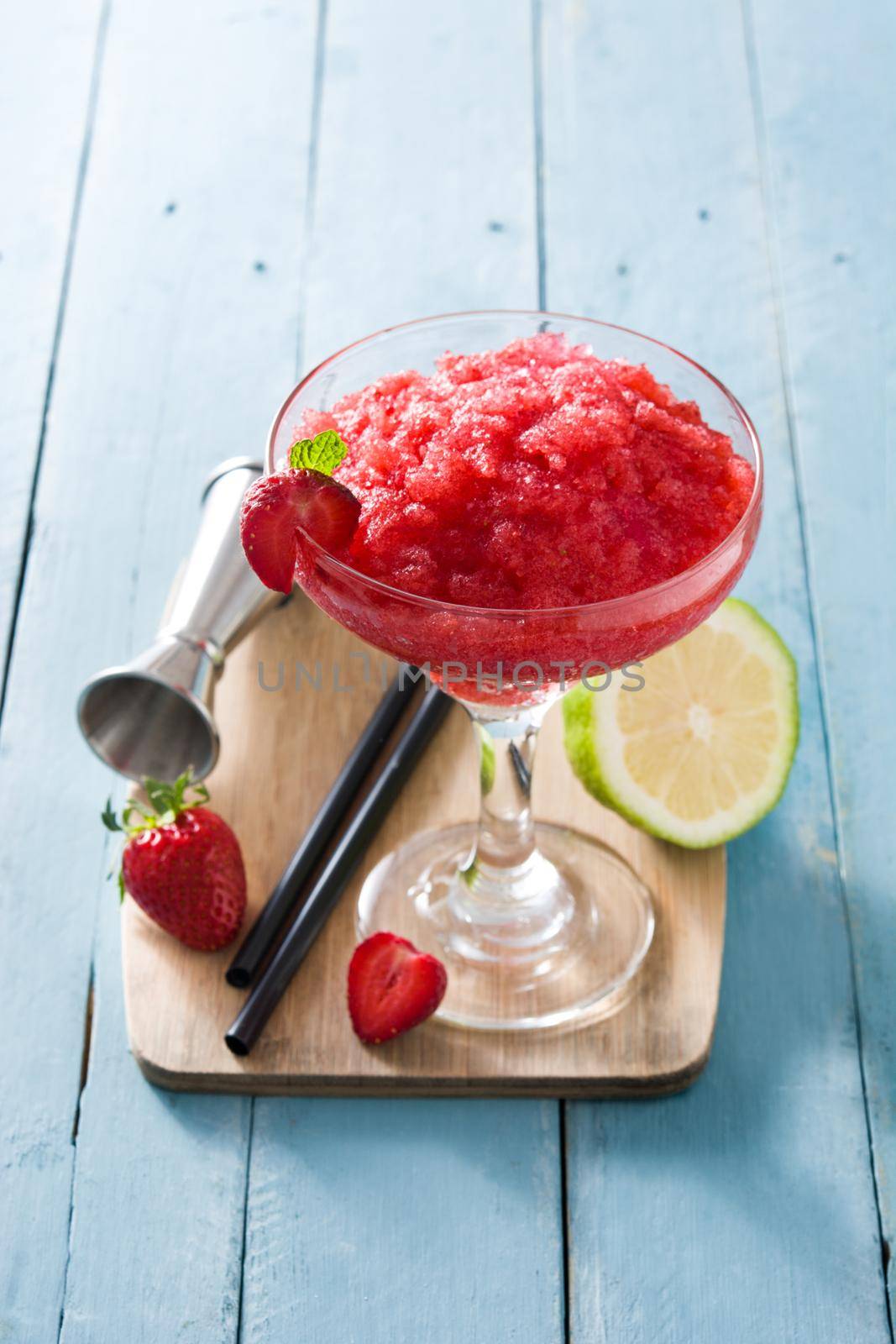 Strawberry margarita cocktail in glass on blue wooden table