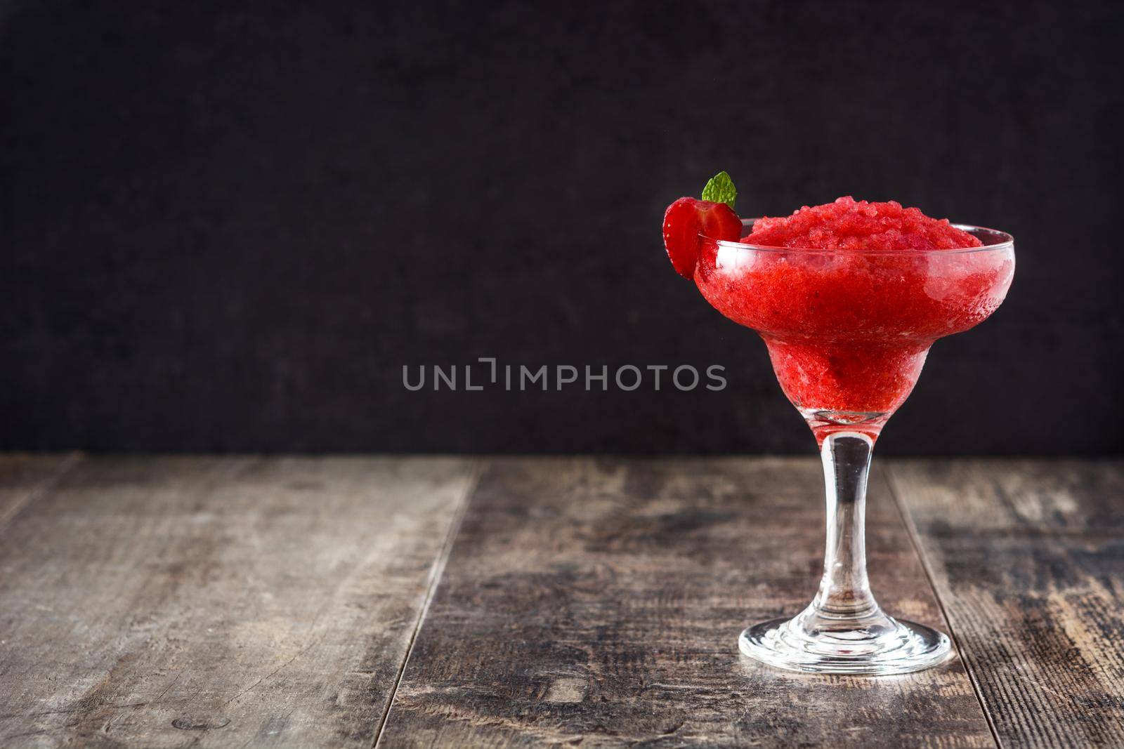 Strawberry margarita cocktail in glass on wooden table.