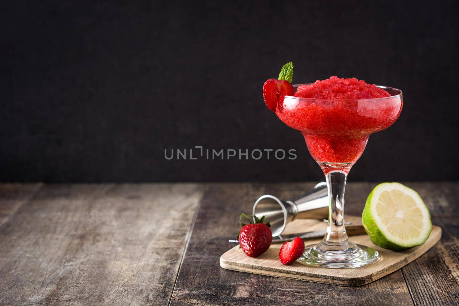 Strawberry margarita cocktail in glass on wooden table.
