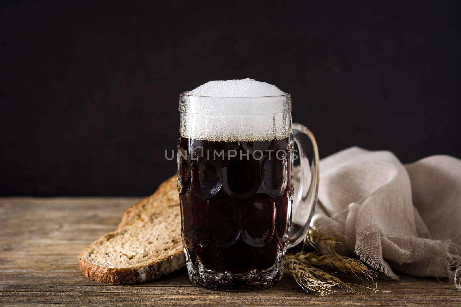 Traditional kvass beer mug with rye bread on wooden table