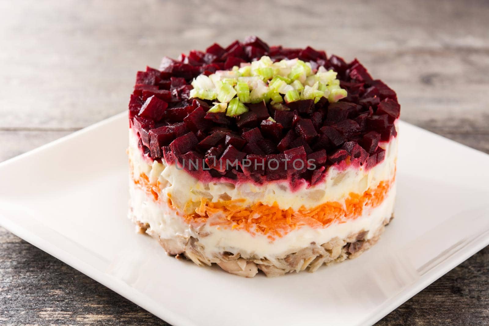 Traditional Russian herring salad with beetroot and carrots on wooden table