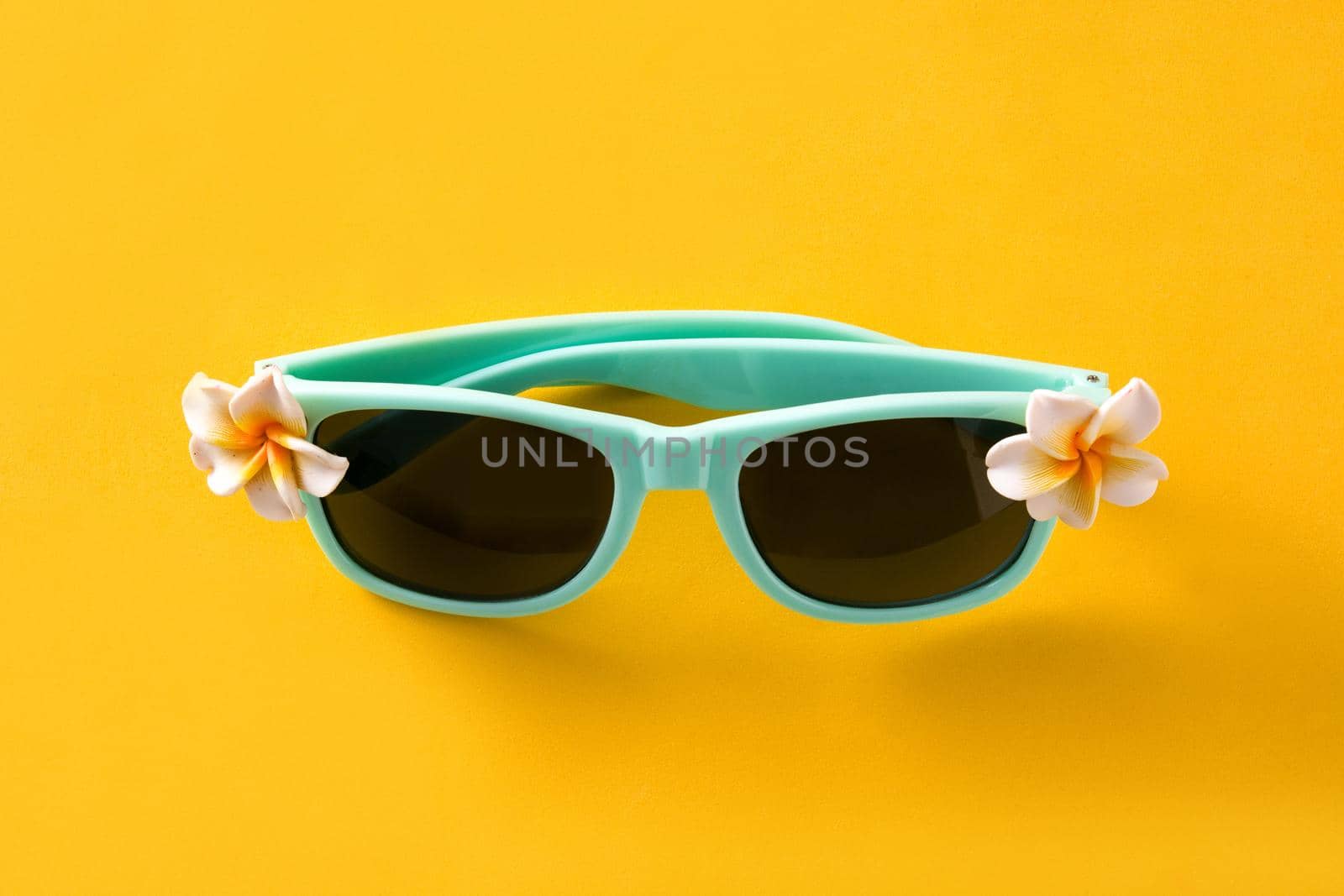Sunglasses with flowers on yellow background