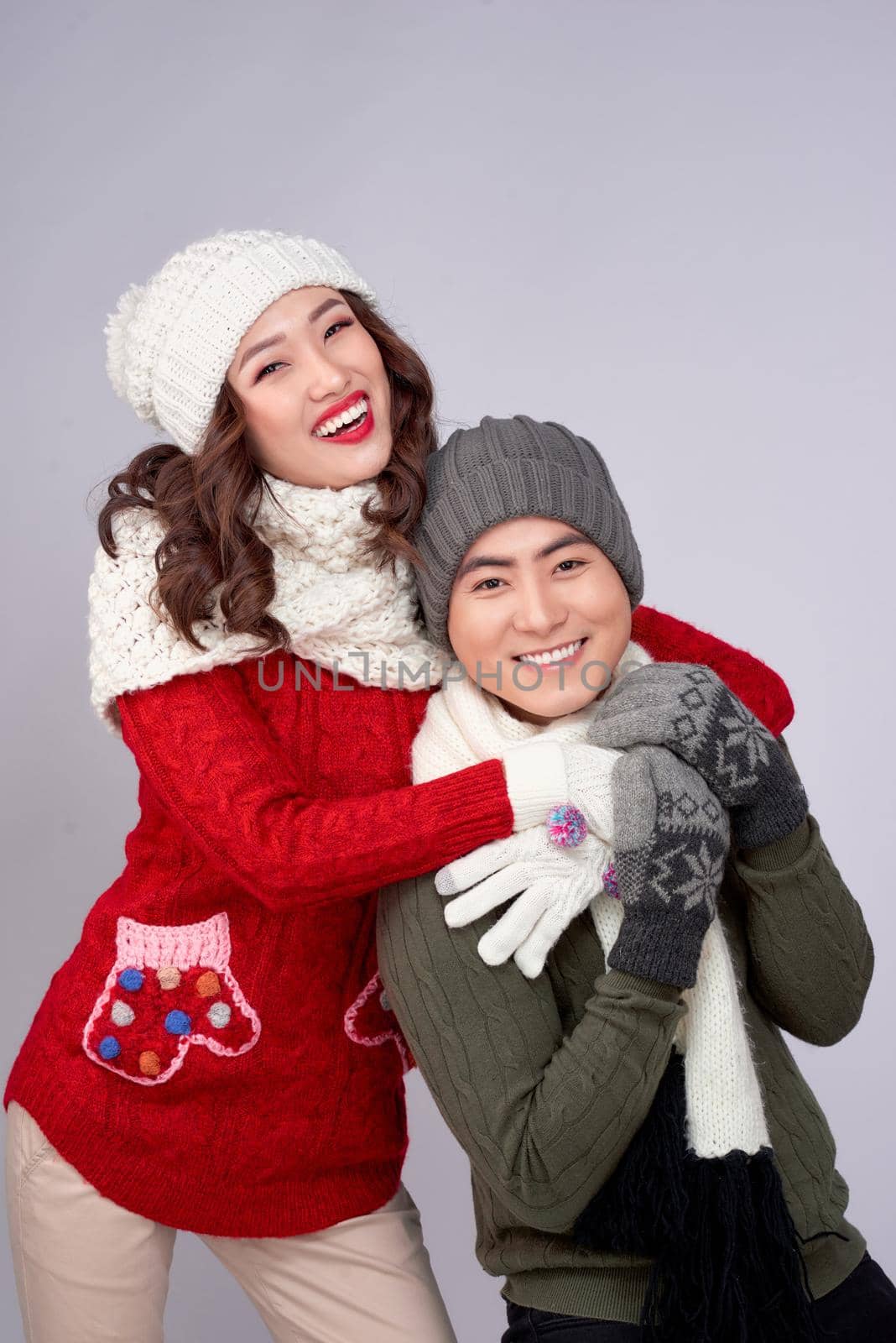 Happy young lovers in knitted woolen clothing hugging and looking together.