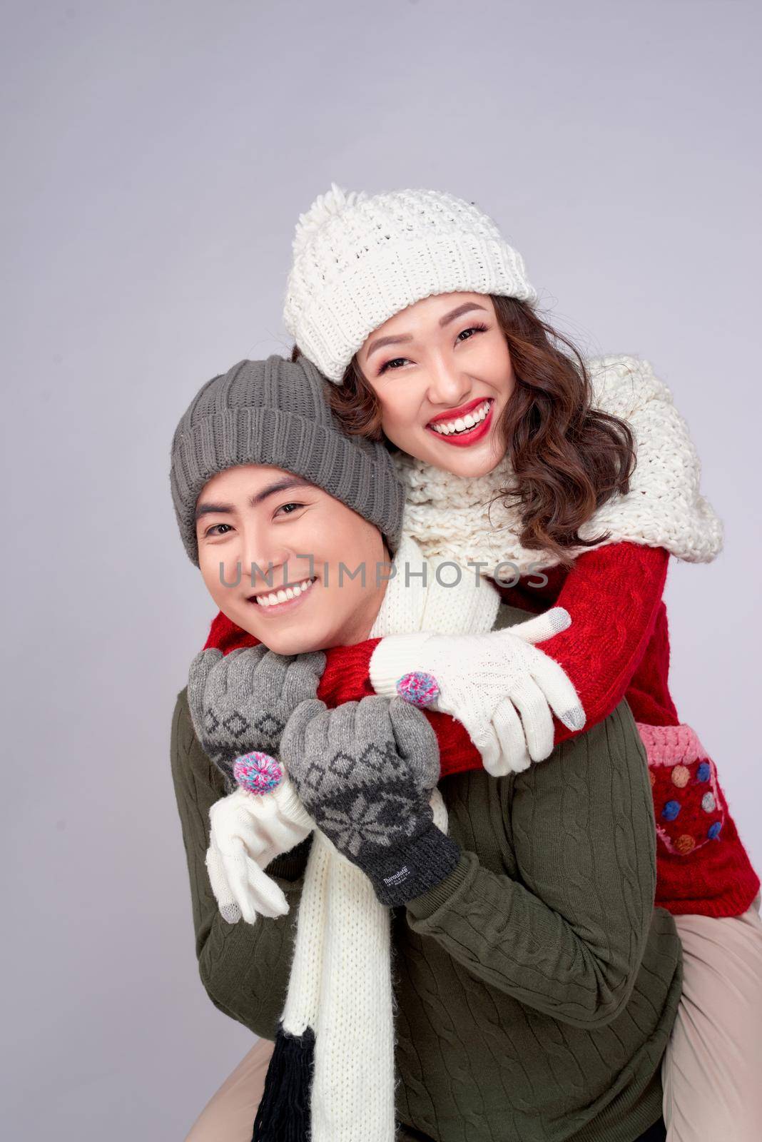 Happy young lovers in knitted woolen clothing hugging and looking together.