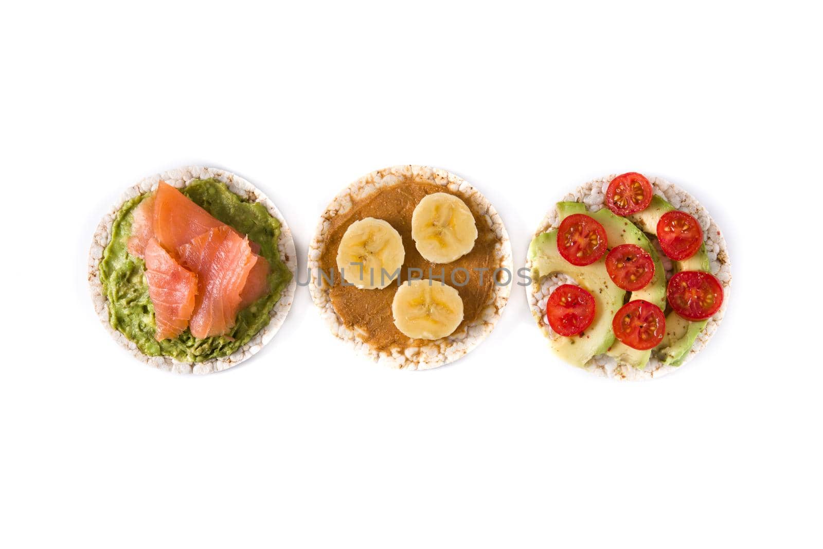 Puffed rice cakes with guacamole salmon,tomato and avocado, and banana with peanut butter isolated on white background