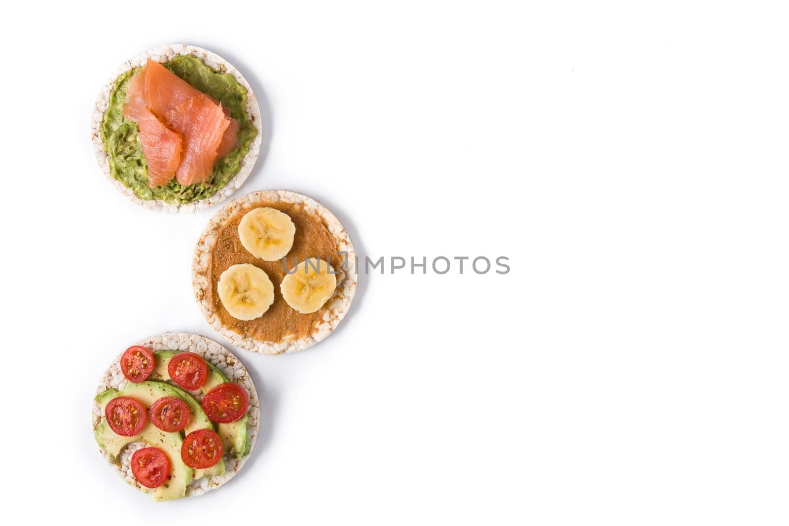 Puffed rice cakes with guacamole salmon,tomato and avocado, and banana with peanut butter isolated on white background