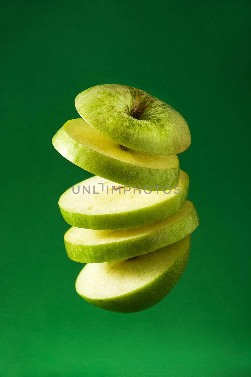 Sliced green apple cut  on green background