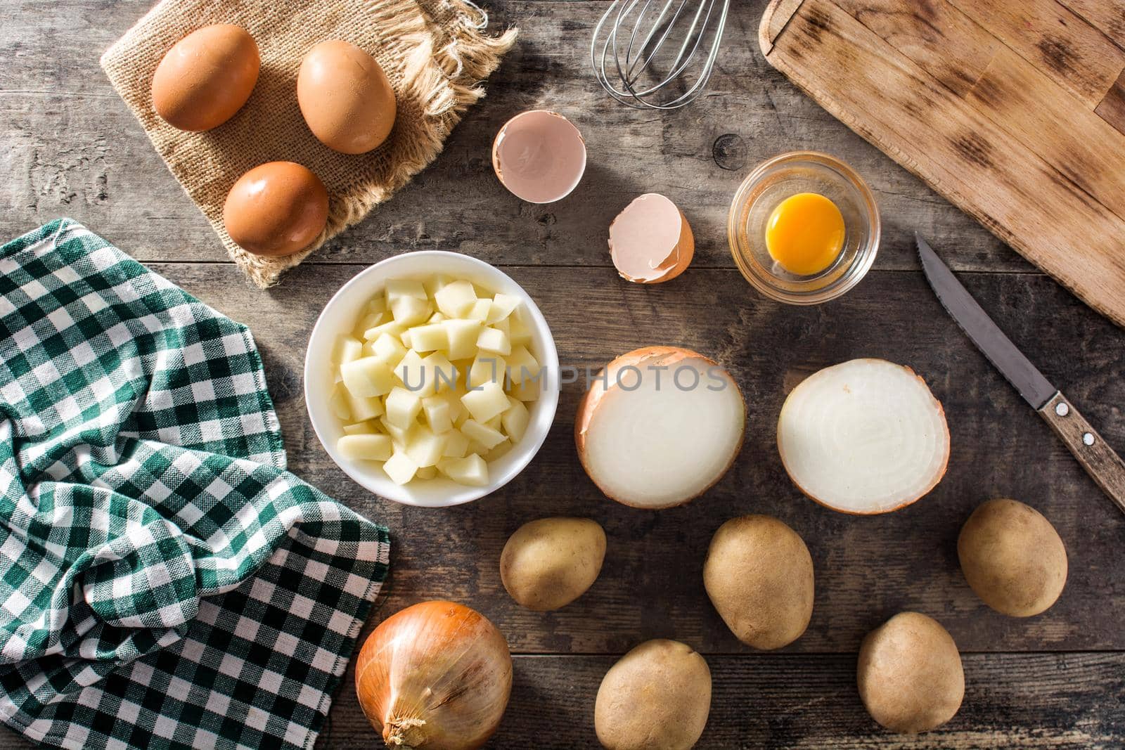 Spanish omelette tortilla ingredients: eggs, potatoes and onion on wooden table
