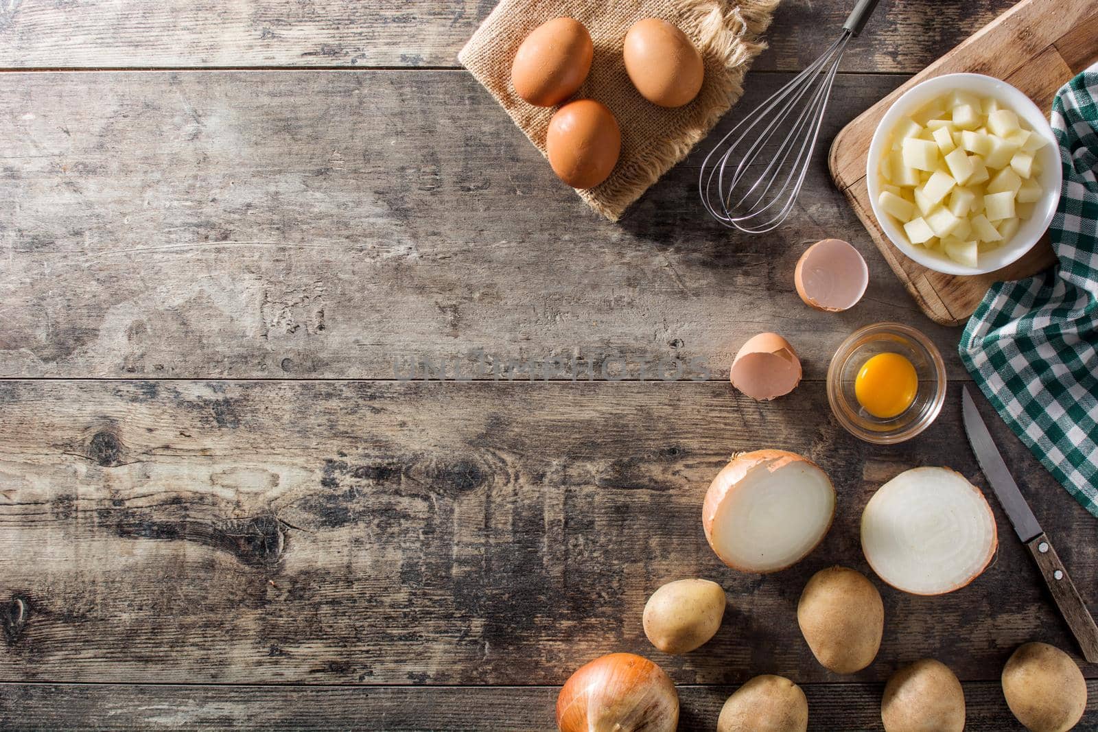 Spanish omelette tortilla ingredients: eggs, potatoes and onion on wooden table