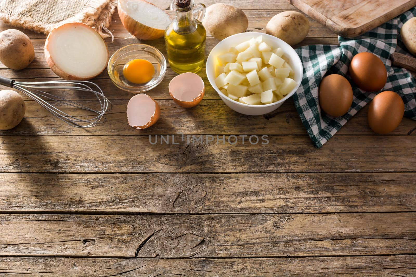 Spanish omelette tortilla ingredients: eggs, potatoes and onion on wooden background. Top view copy space