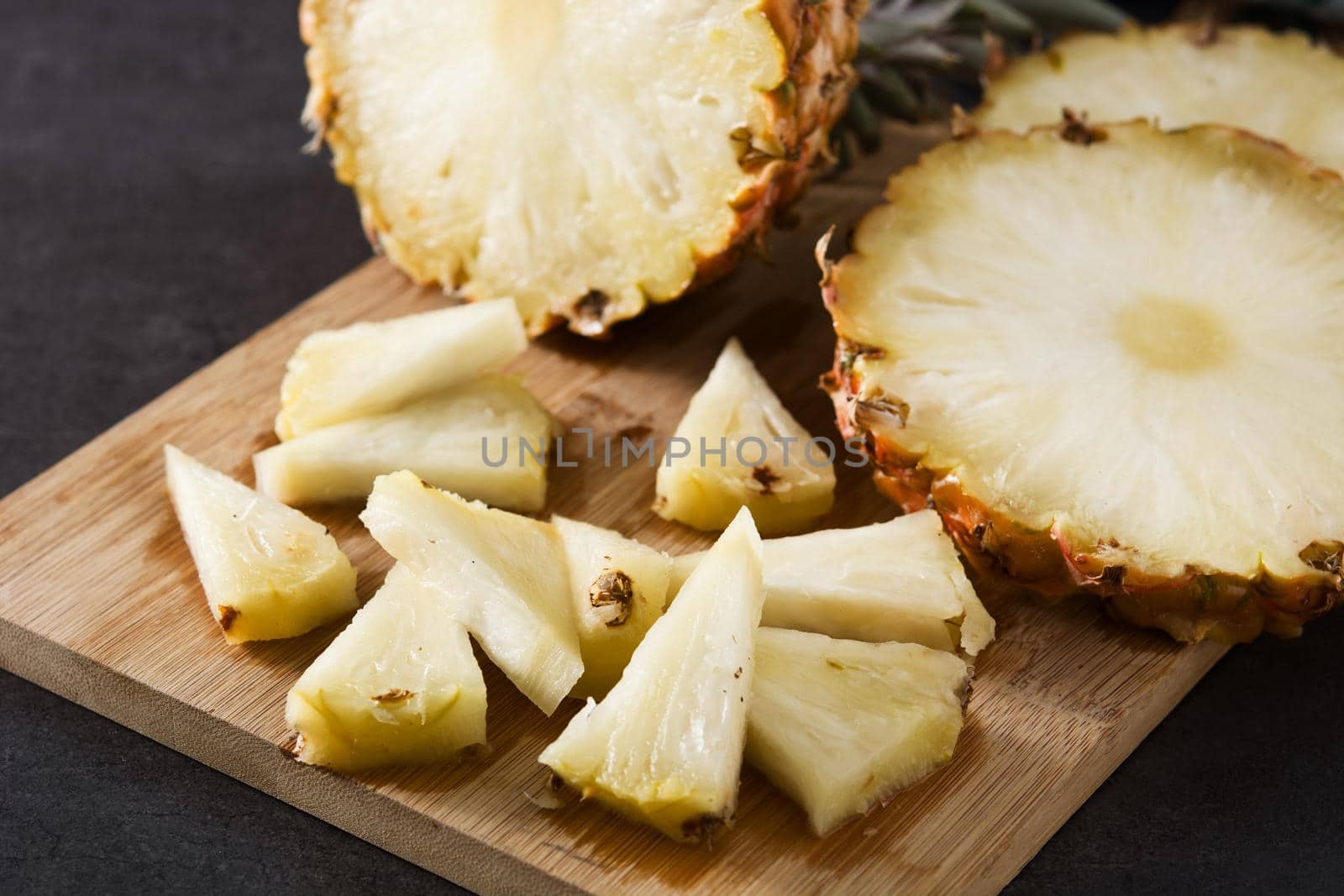 Fresh pineapple slices on black slate background