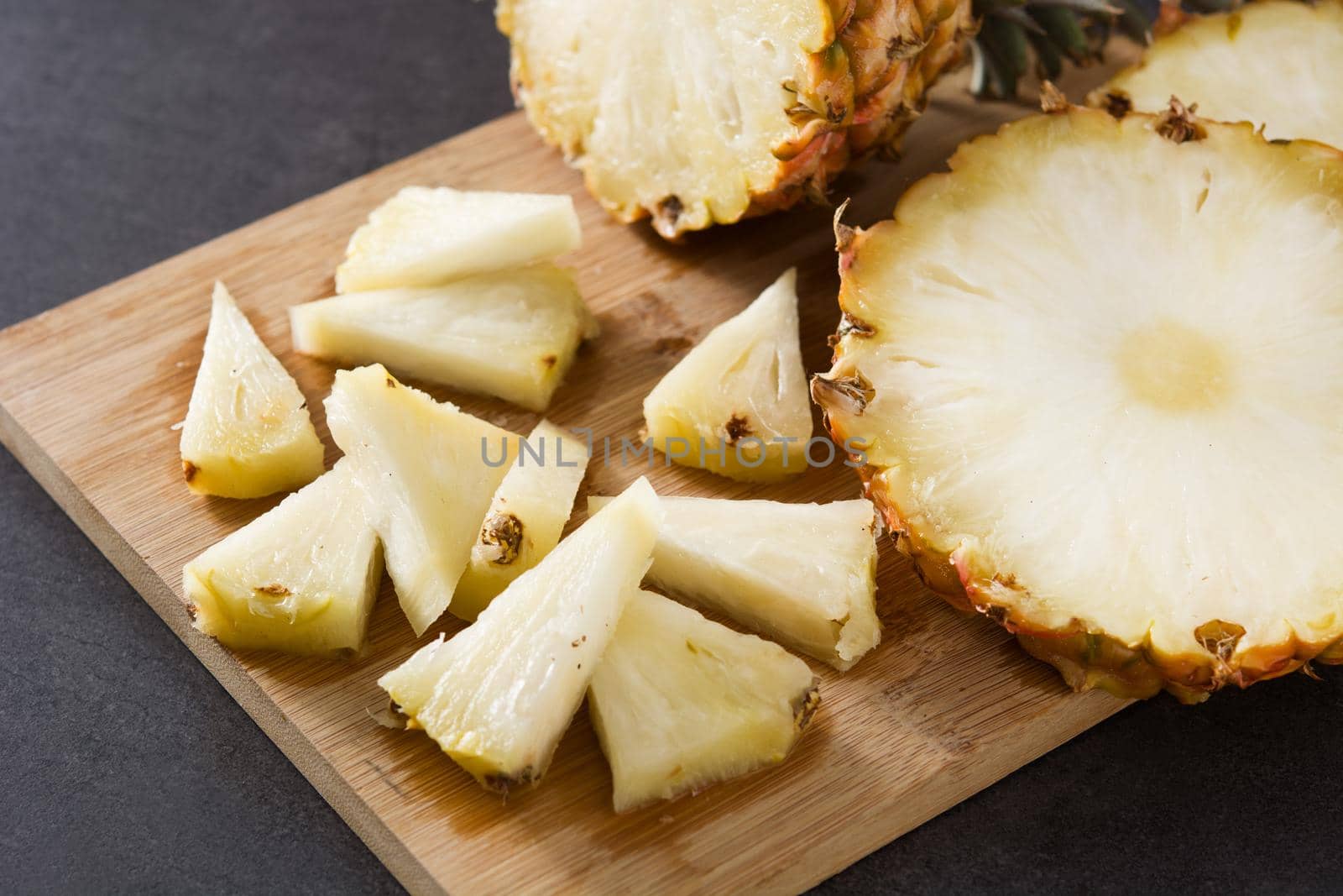 Fresh pineapple slices on black slate background