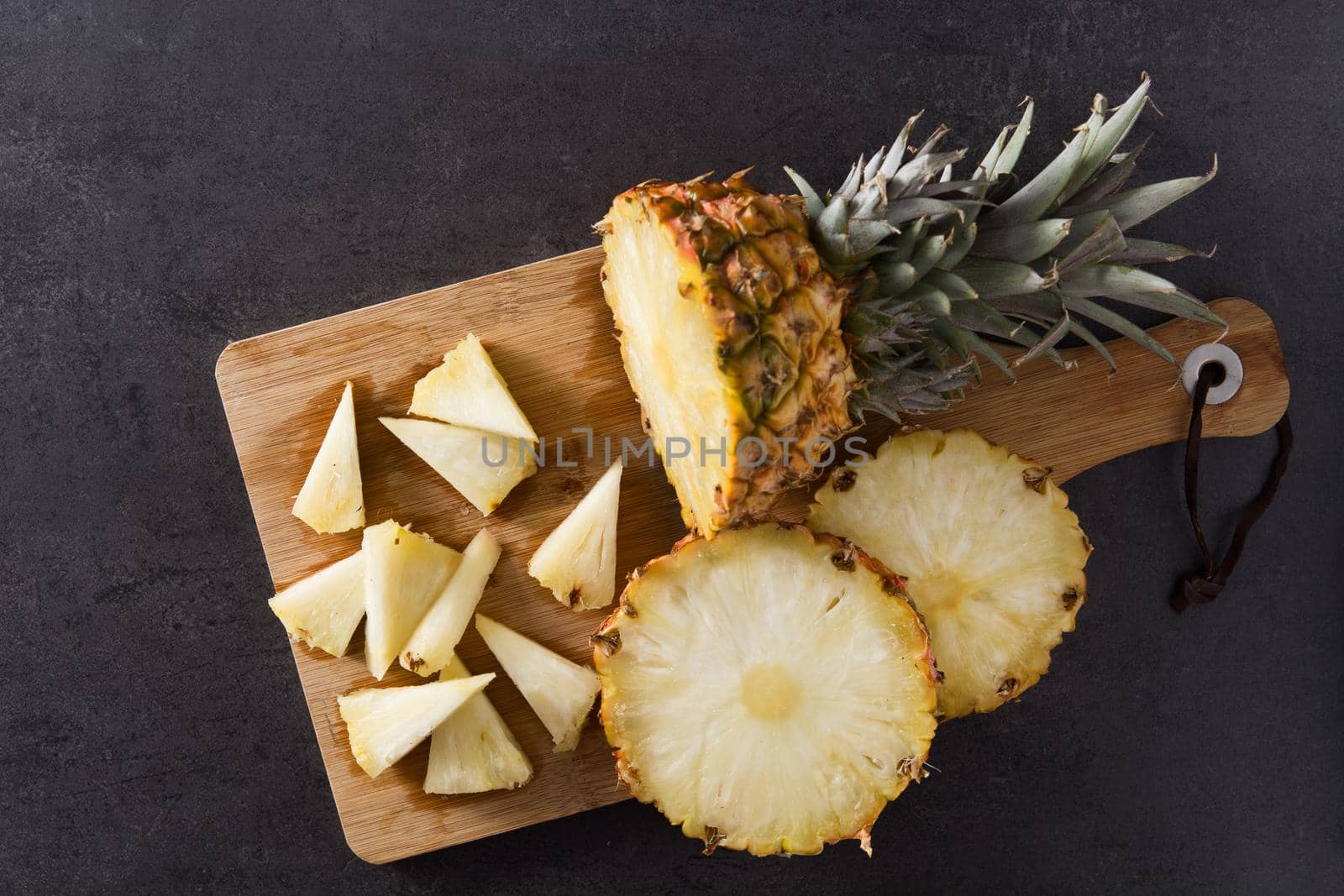 Fresh pineapple slices on black slate background