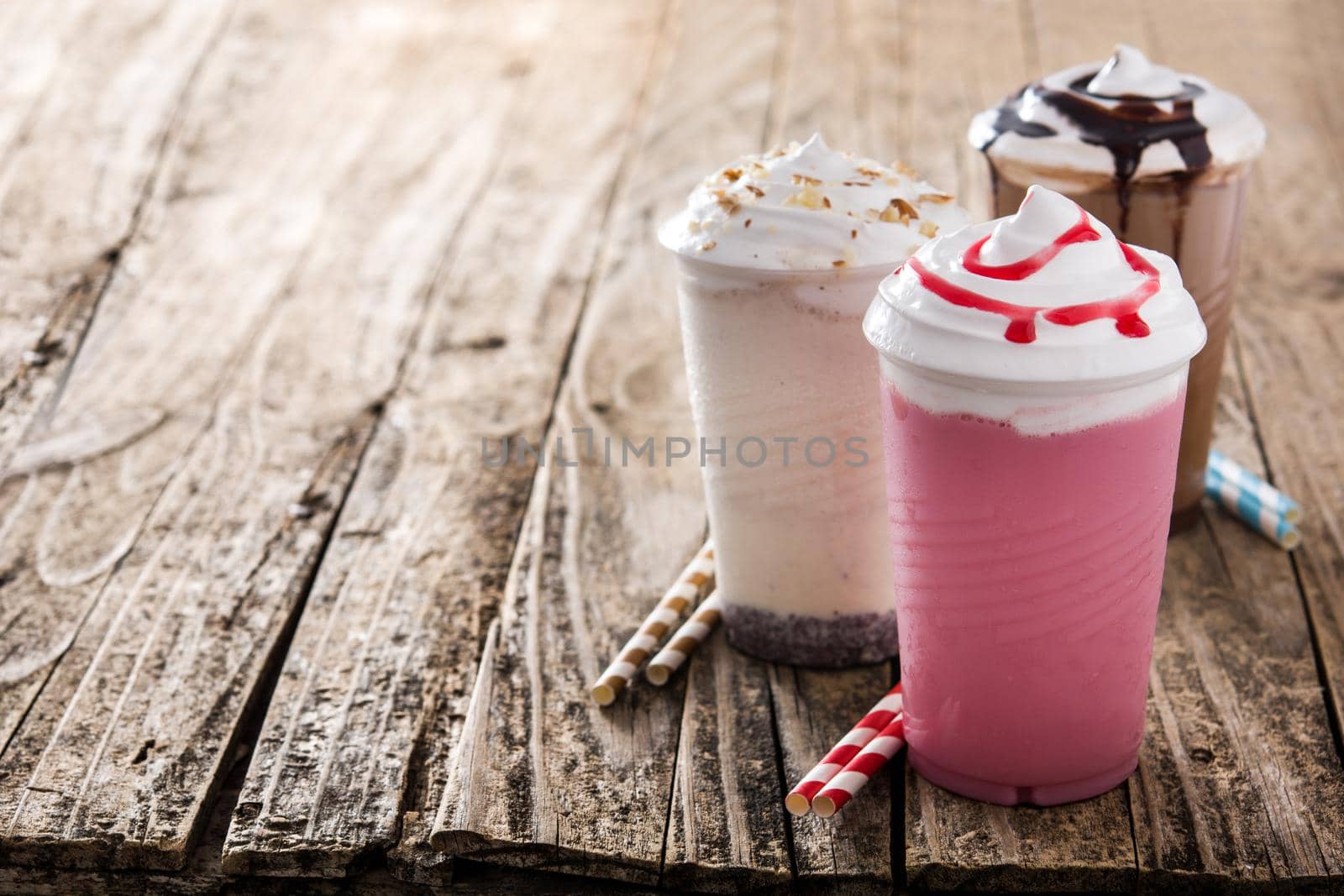 Strawberry, chocolate and white milkshakes on wooden table