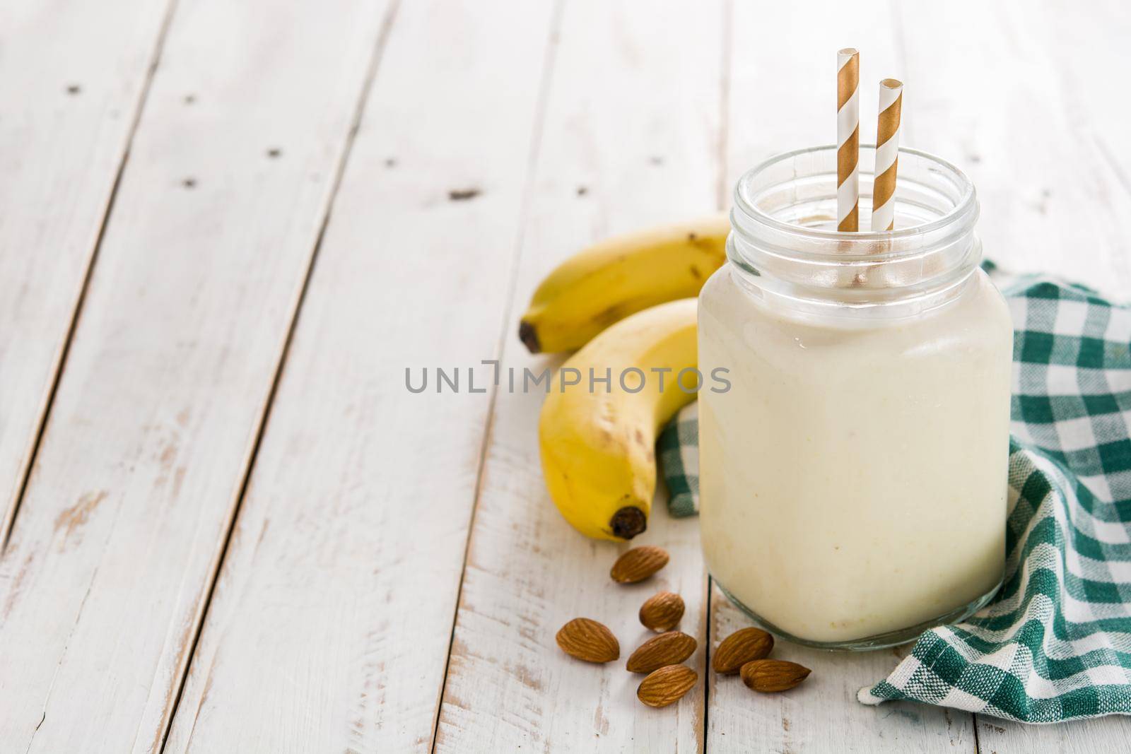 Banana smoothie with almond in jar on wooden table