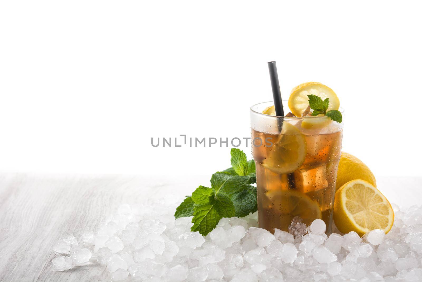 Iced tea drink with lemon in glass and ice on white wooden table