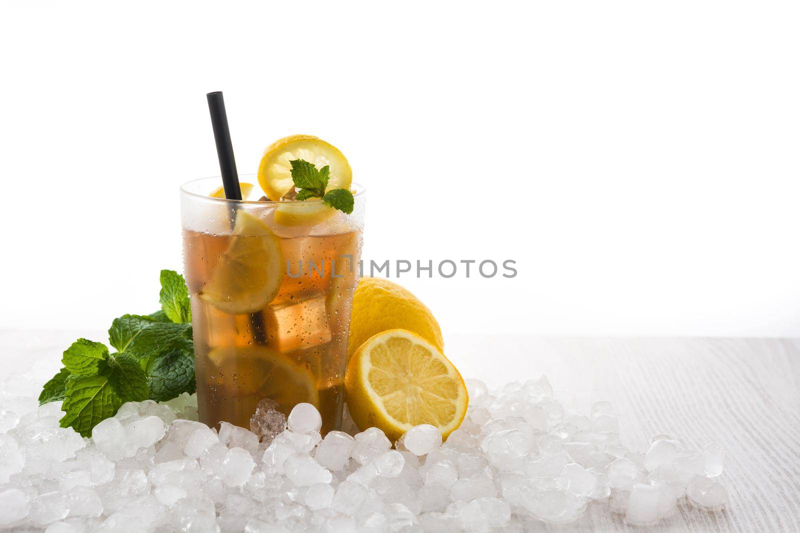 Iced tea drink with lemon in glass and ice on white wooden table