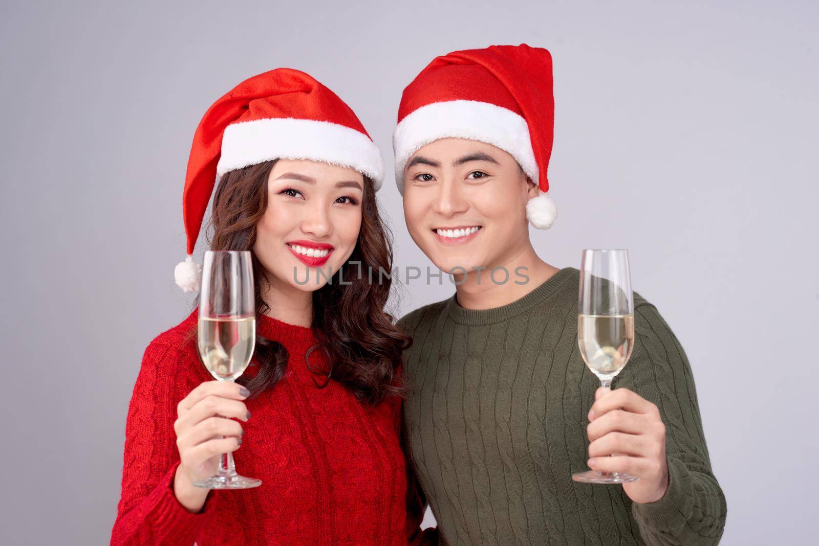 Asian couple wearing christmas hat and dress holding champagne glass by makidotvn