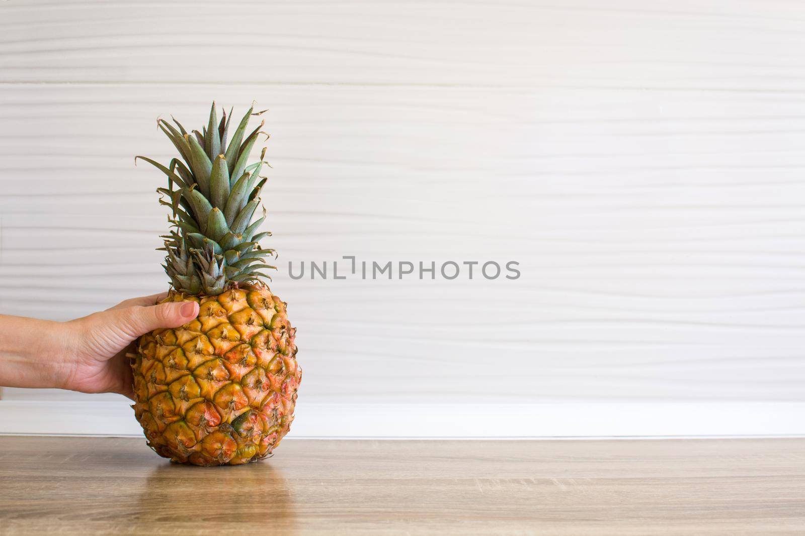 Female hand picking up a pineapple in the kitchen