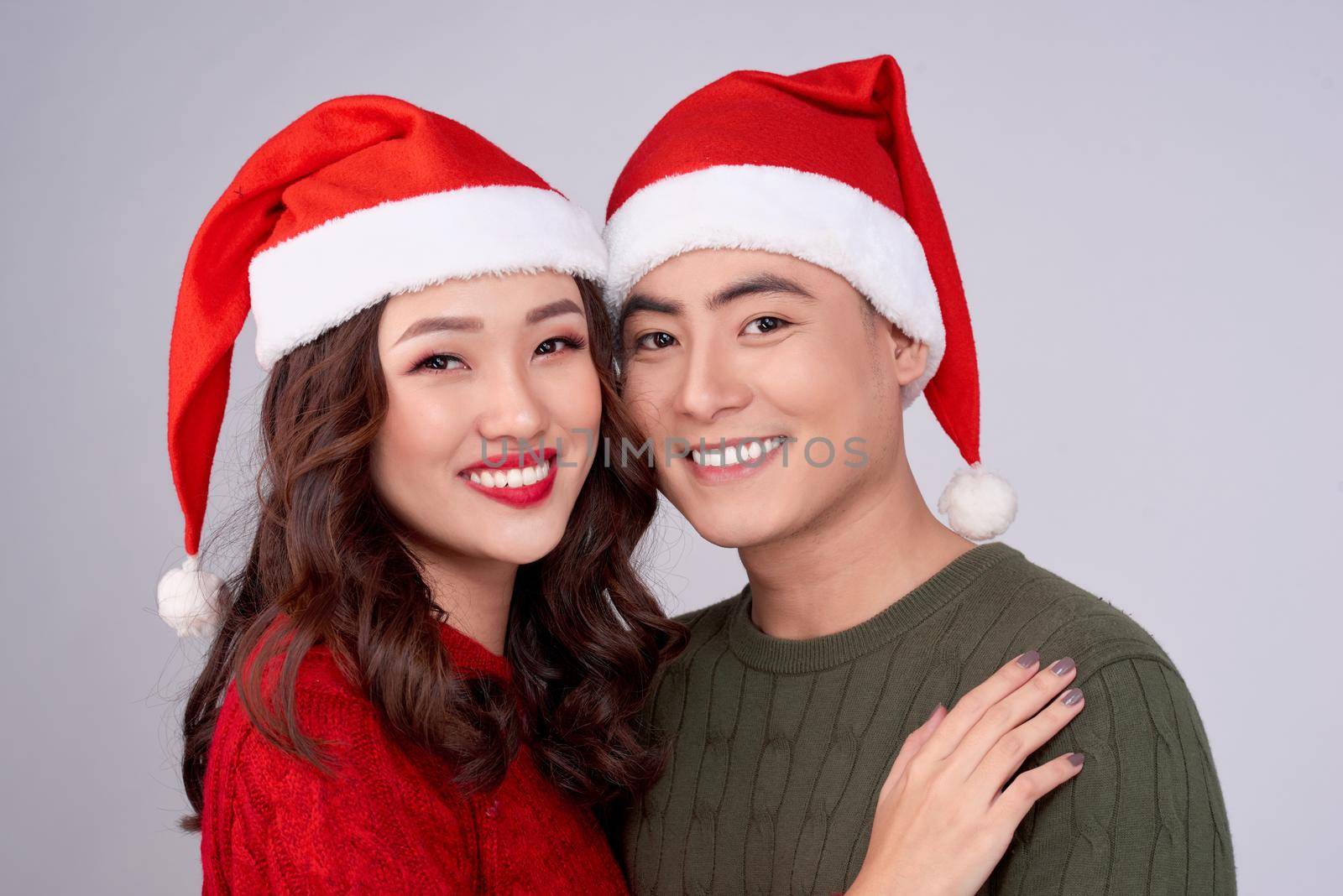 Happy young lovers in knitted woolen clothing hugging and looking together.