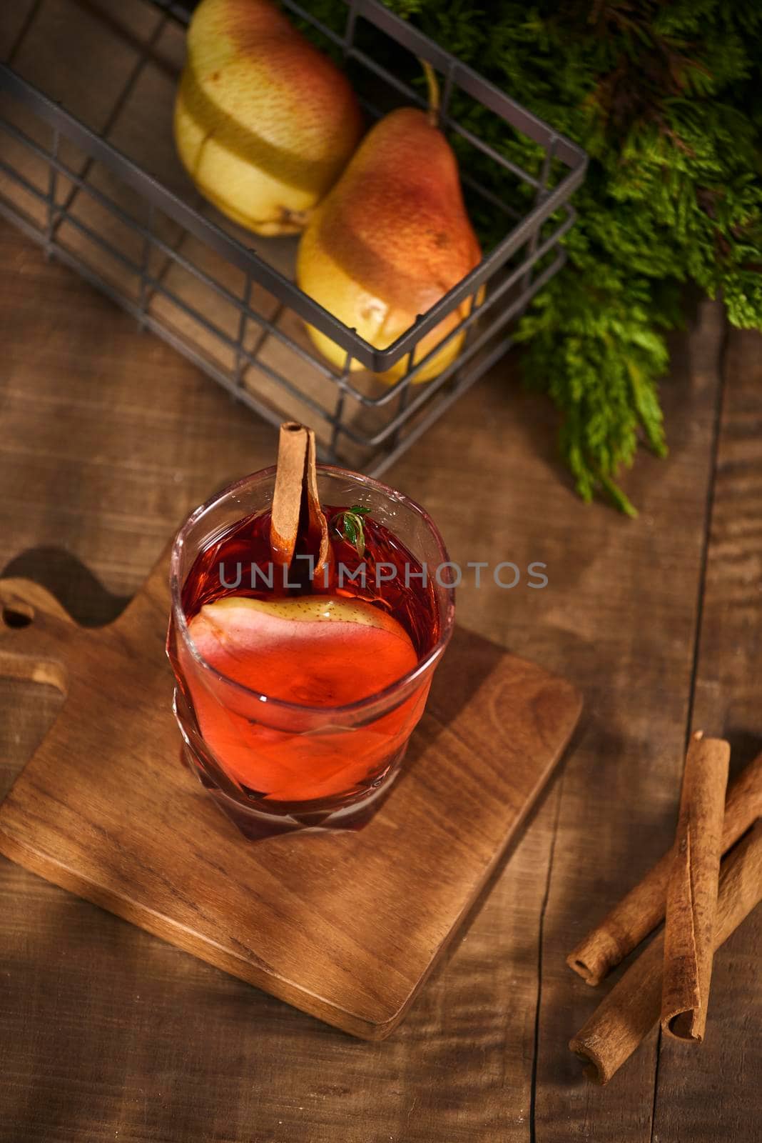 Glass of Cider pear cocktail or lemonade, cinnamon sticks, anise stars on wooden background.