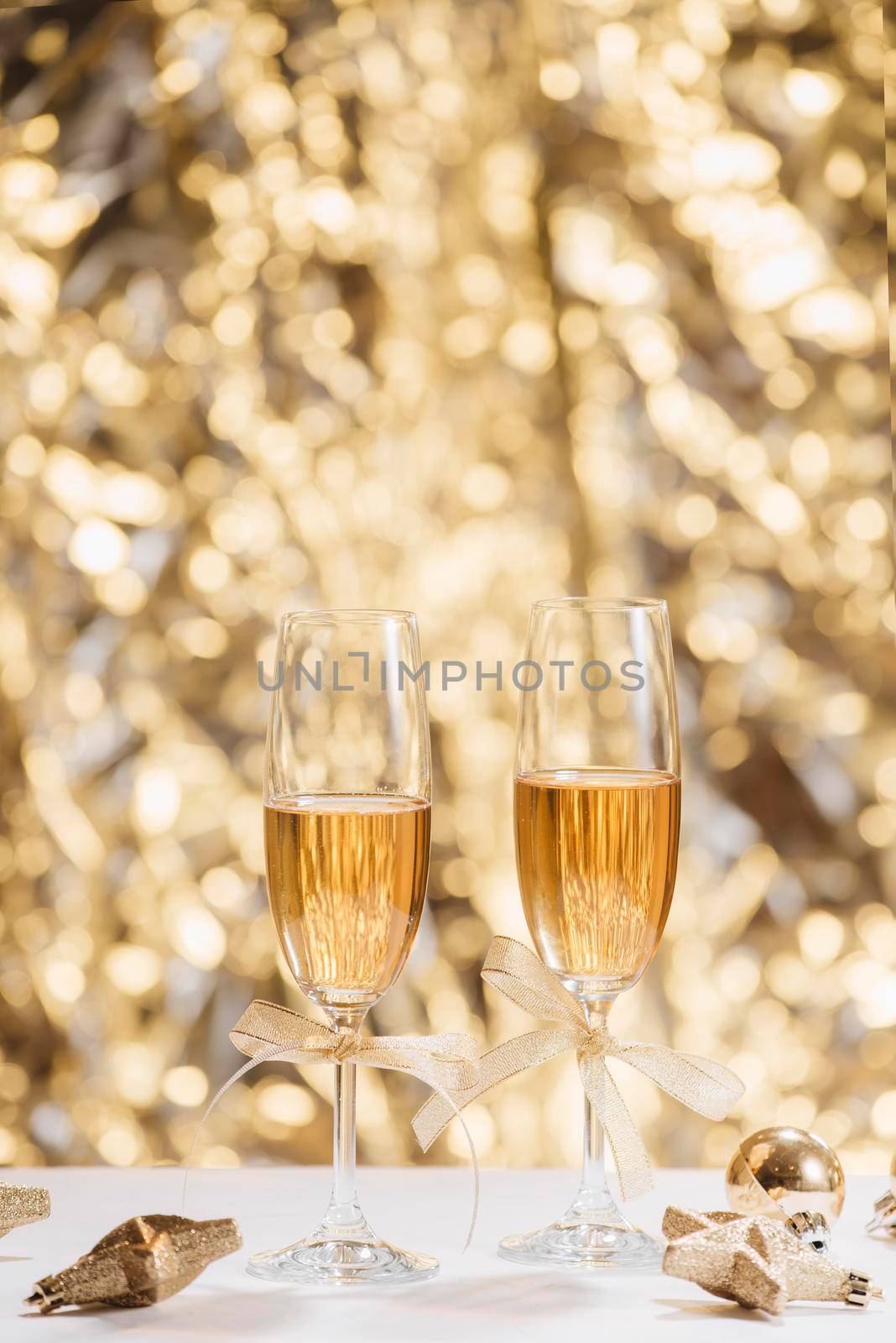 Two full champagne glasses with bokeh lights in the background