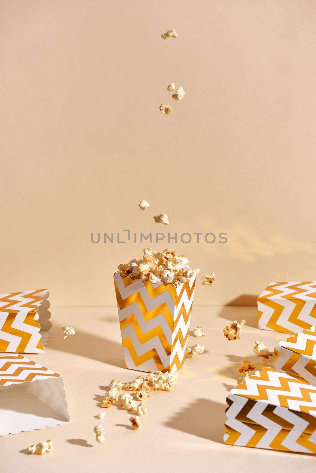 Salty fresh crusty homemade popcorn in golden paper cup in the fashion beige background in a New Year"s interior. selective focus