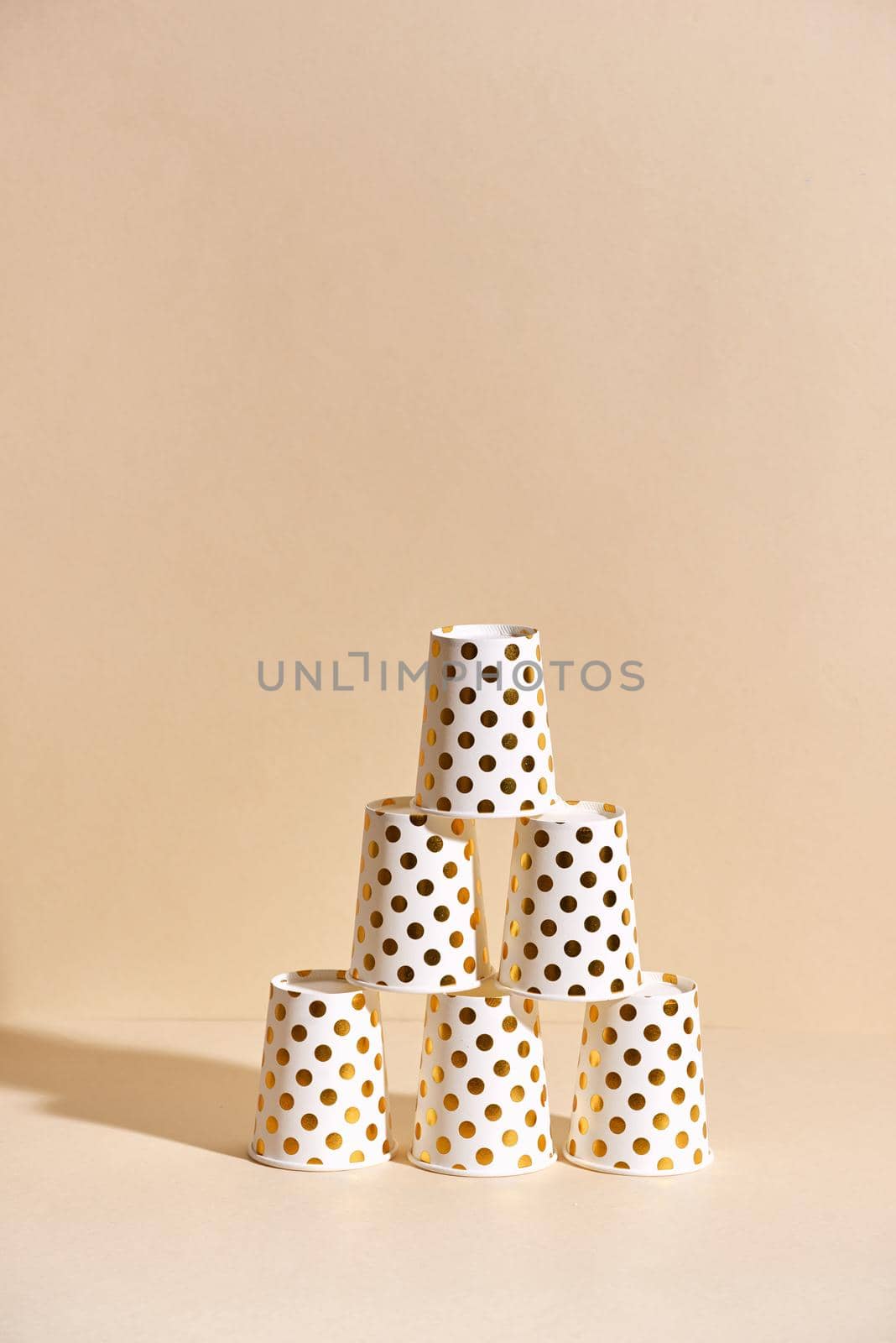 Golden polka dot paper cup isolated on beige background