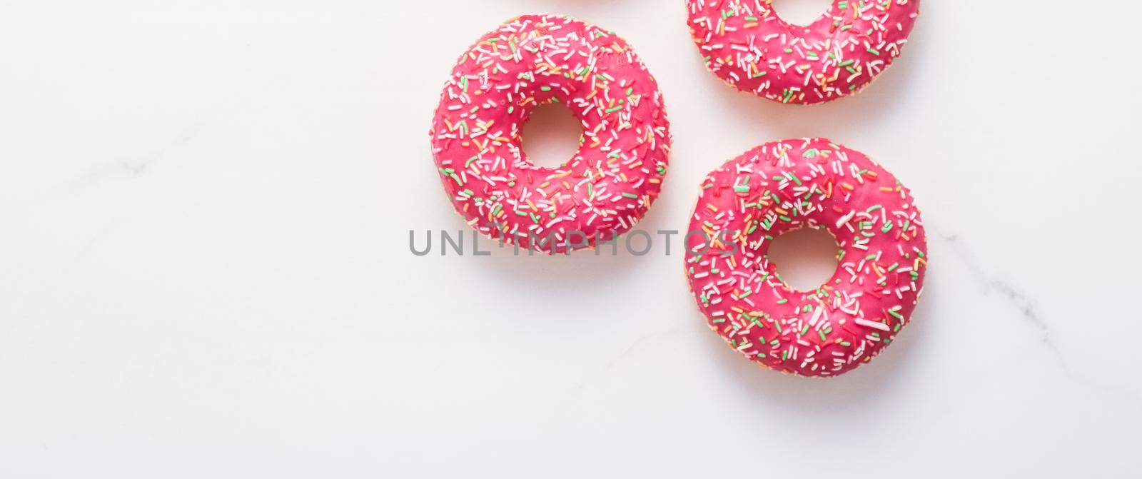 Bakery, branding and cafe concept - Frosted sprinkled donuts, sweet pastry dessert on marble table background, doughnuts as tasty snack, top view food brand flat lay for blog, menu or cookbook design