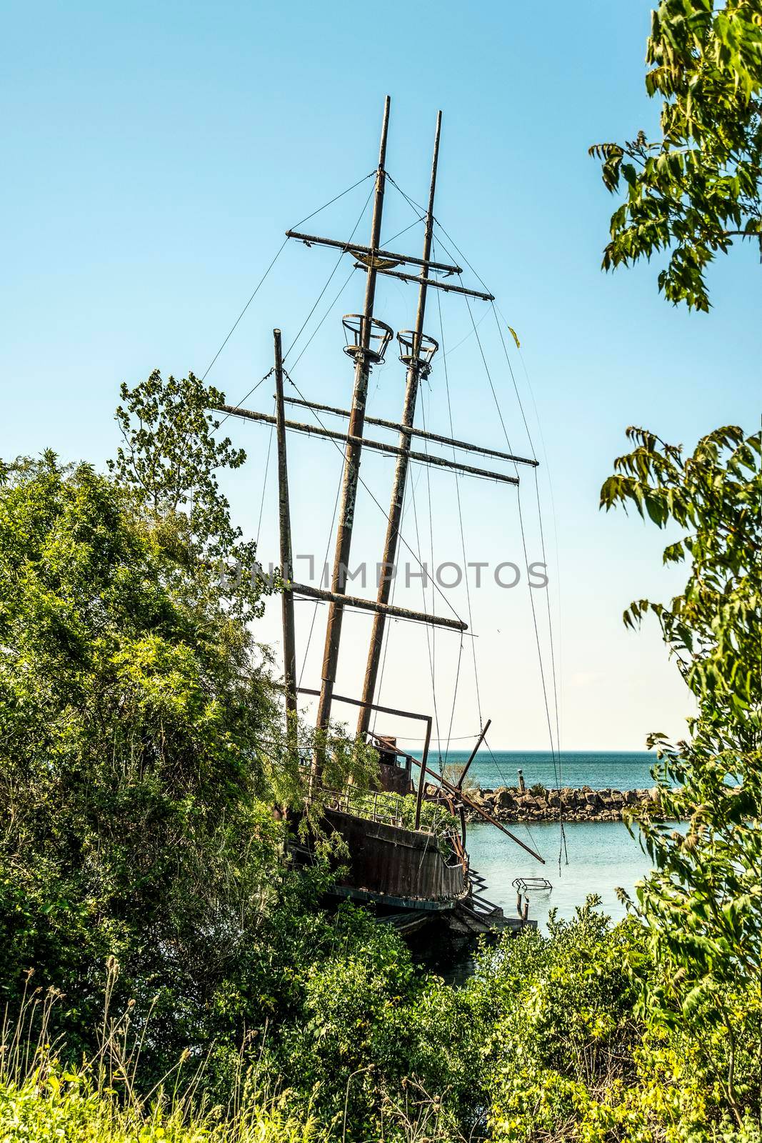 On one of the lakes in Ontario, on the dock, a rusting three-masted ship is living out its last days.