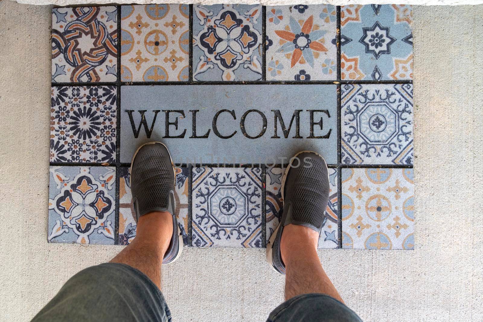 In front of the entrance to the house on the rug the feet of a person standing in front