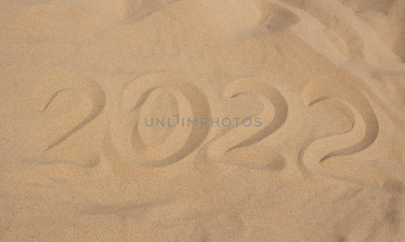 The numbers 2022 in the sand. The concept of the New Year 2022. Summer holidays and sea trips.