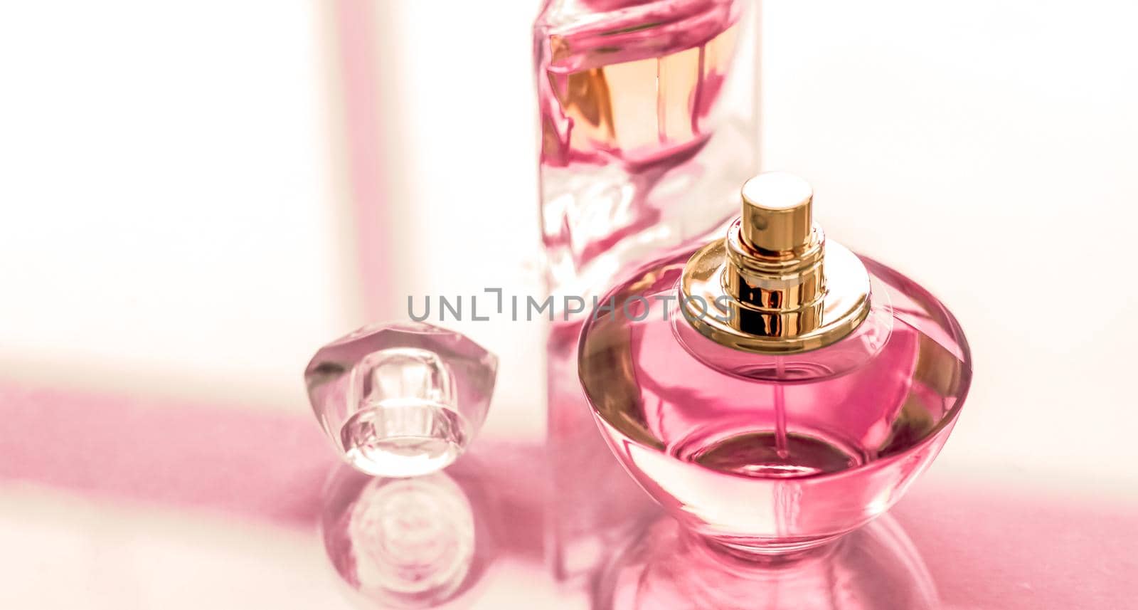 Perfumery, spa and branding concept - Pink perfume bottle on glossy background, sweet floral scent, glamour fragrance and eau de parfum as holiday gift and luxury beauty cosmetics brand design